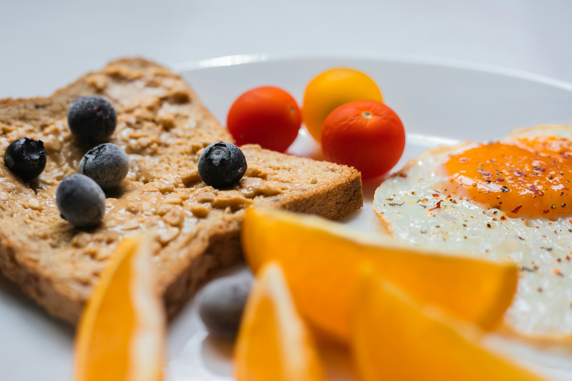 Healthy Routines sliced bread with sliced orange and blueberries on white ceramic plate